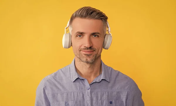 Улыбающийся человек слушать музыку в наушниках на желтом фоне, технологии — стоковое фото
