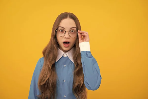 Удивлённая девушка-подросток чинит очки желтым фоном, сюрприз — стоковое фото