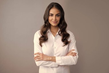 Mutlu kendine güvenen iş kadını gülümser kollarını kavuşturur gri arka plan, kendine güven