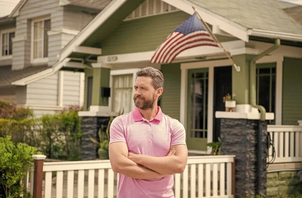 Bärtiger Mann Makler verkaufen oder vermieten Haus mit amerikanischer Flagge, Haus — Stockfoto