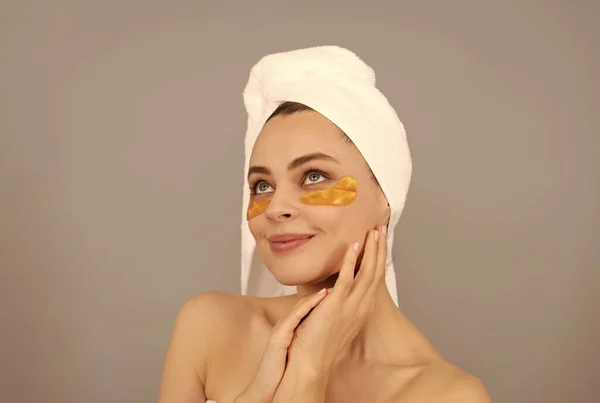 Gadis cantik dengan handuk terry menggunakan penutup mata emas wajah untuk kulit, keindahan — Stok Foto