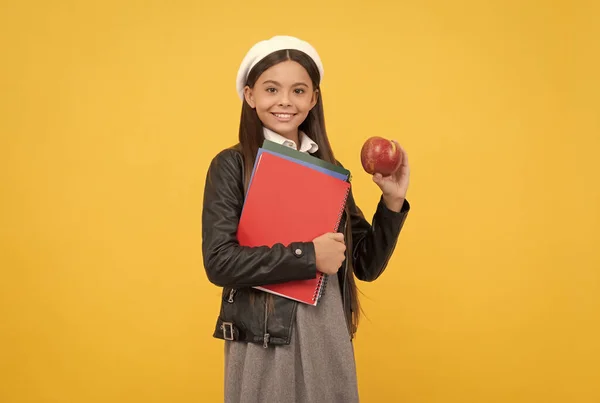 Детское питание. Счастливая девочка-подросток держит яблоко и книги. Школьное питание. Вегетарианская диета — стоковое фото