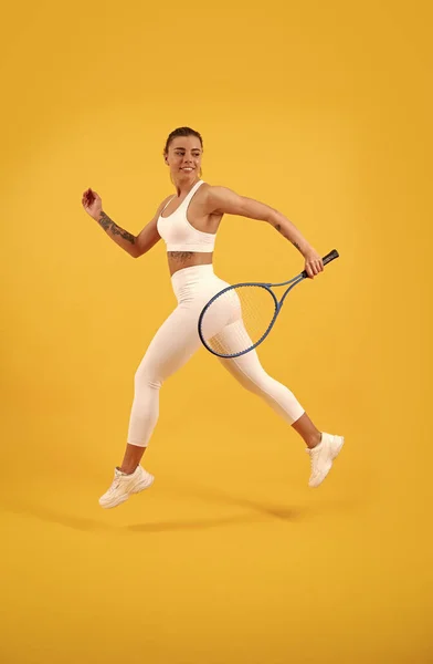 Gioco di sport e hobby. attività estiva. sorridente ragazza in abbigliamento sportivo correre con racchetta. — Foto Stock