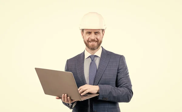 Gelukkig man in pak en veiligheid helm wotking op computer online geïsoleerd op wit, behendig bedrijf. — Stockfoto