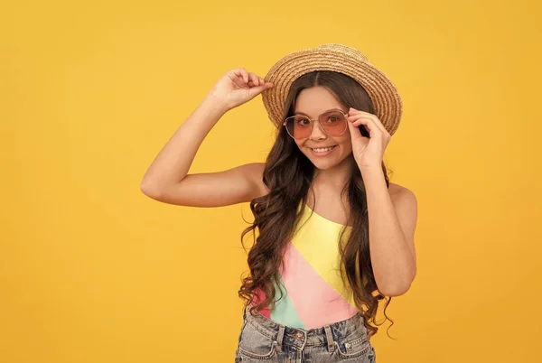 Gelukkig kind in de zomer stro hoed en bril heeft krullend haar op gele achtergrond, zomer plezier — Stockfoto