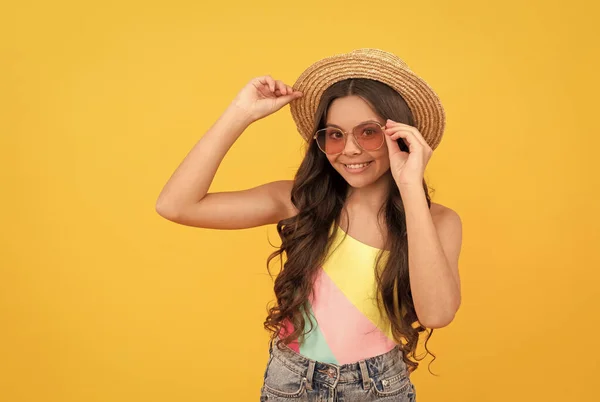 Heureux enfant en été chapeau de paille et lunettes a les cheveux bouclés sur fond jaune, plaisir d'été — Photo