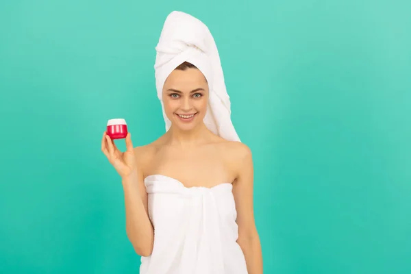 Cheerful lady in towel with skin cream on blue background — Stock Photo, Image