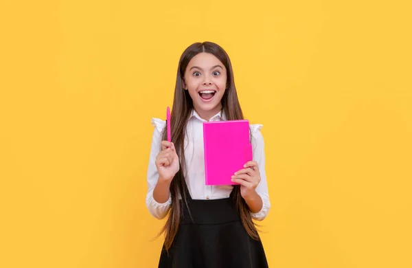 Šťastné dítě génius držet školní knihu ukazující nahoru žluté pozadí, nápad — Stock fotografie