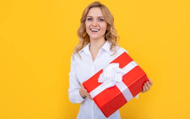 Sarı arka planda büyük hediye kutusu olan pozitif kadın.