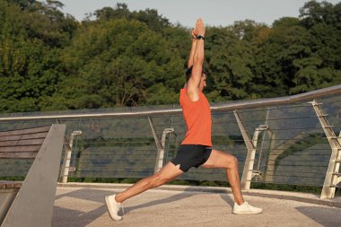 Kalçandaki gerilmeyi hisset. Hilal hamlesi yapan adam kollarını kaldırıyor. Yoga ya da pilates yaparken.