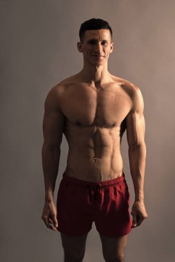 Formda olduğum için mutluyum. Atletik adam gri arka plan. Spor şortlu üstsüz adam. Sporcu