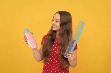 Mutlu çocuk uzun saçlarını tarıyor. Kuaför. Kızın dalgalı saç fırçası var.