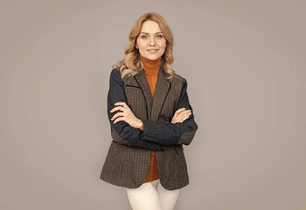 Usmívající se podnikatelka v anglickém oblečení na šedém pozadí. veselé blondýny žena v bundě — Stock fotografie