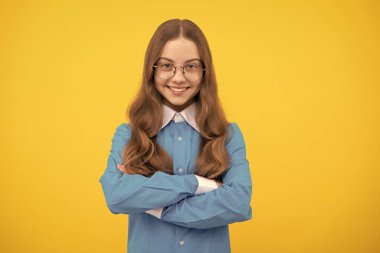 Gözlüklü, kendine güvenen mutlu gülümseyen, kollarını çapraz tutan, kendine güvenen genç kız.