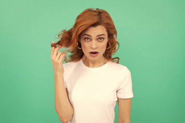 Şaşırmış kızıl saçlı kız mavi arka planda kıvırcık saçlı, sürpriz.