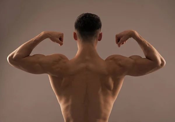 Přizpůsobit muž zadní část trupu ohyb paže sval ukazující biceps triceps šedé pozadí, ohýbání — Stock fotografie