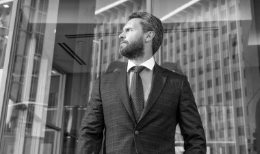 Resmi takım elbiseli, kendine güvenen sakallı iş adamı.