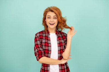 Mavi arka planda kareli tişörtlü, şaşkın kızıl kız.