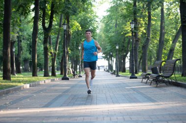 Spor kıyafetleri içinde koşan sağlıklı atletik bir adam.