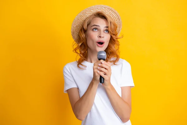 Beautiful young woman singing karaoke isolated on yellow. Girl singing soundtrack song at mic.