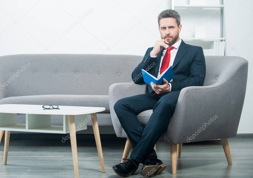 mature businessman in suit sit in office with business planner