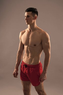 Spor şortlu, kaslı atletik adam gri arka planda, adamım..