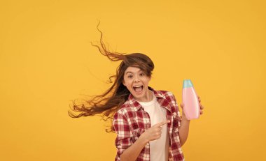 Günlük alışkanlıklar ve kişisel bakım. Kozmetik ürünleri sunuyorum. Güzellik. Çocuk duş jeli kullanıyor. Şampuan şişeli mutlu genç kız. Kuaförde saç şampuanlıyordum. Saç kremi kullanan bir çocuk. uzun kıvırcık saçlar.