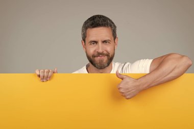 Sarı kağıdın arkasına sakallı, gülümseyen, gülümseyen, başparmağını gösteren, onaylı bir adam..