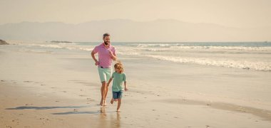 Baba ve oğul yaz plajında koşuyor. Aile seyahati ve tatil. Çocukluk ve ebeveynlik. Babası denizdeki ya da okyanustaki çocukla birlikte. Hafta sonu aile günü. Baba ve çocuk dışarıda eğleniyor. Boşluğu kopyala