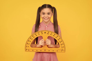 Happy child hold school math tool exractor cetvel sarı arka planda, okul.
