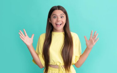 Güzellik ve moda. Kadın manken. Genç bir kızın güzel görünüşü. Mavi arka planda çocuk portresi. Olumlu duygularını ifade et. Uzun saçlı, şaşkın bir çocuk..