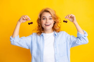 Sarıya izole edilmiş vişne tabağı olan çekici bir kadın. Şaşırmış kadın yüzü