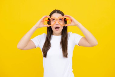 Komik parti gözlükleri takan neşeli bir kız. Sarı arka planda izole edilmiş komik gözlükler takan genç kadın portresi