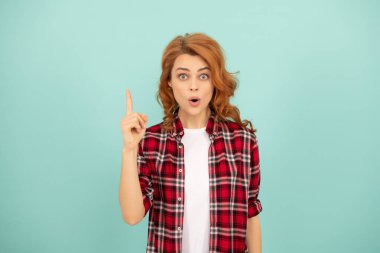 Mavi arka planda kareli tişörtlü, etkileyici kızıl saçlı kız..