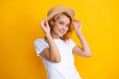 Sarı arka planda hasır şapkalı güzel bir kadının moda portresi.