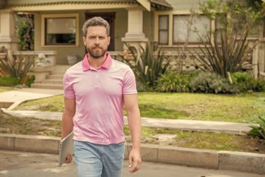 Ciddi sakallı bir emlakçı dizüstü bilgisayarla dolaşıyor, iş adamı..