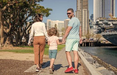Genç bir ailenin çocuk ve aile günüyle parkta yürüyüşünün arkası..
