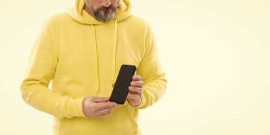 Ürün teklifi. Reklam sunumu. kopyalama alanı. Kesilmiş adam telefon ekranını sunuyor. Beyazda izole akıllı telefon gösteren kırpılmış bir adam. Sarı kapüşonlu adam.