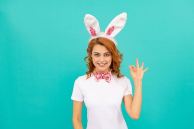 Tavşan kulaklı neşeli Paskalya kadını ve mavi arka planda papyon. Tamam.