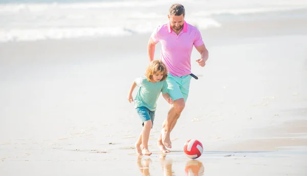 sport activity. father and son play football on beach. daddy with kid boy on active day. weekend family day. dad and child having fun outdoors. childhood and parenting. family holidays.