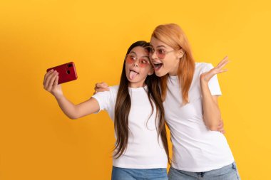 Şaşırmış anne ve kız çocuğu akıllı telefon ve annelik ile selfie çekiyorlar..