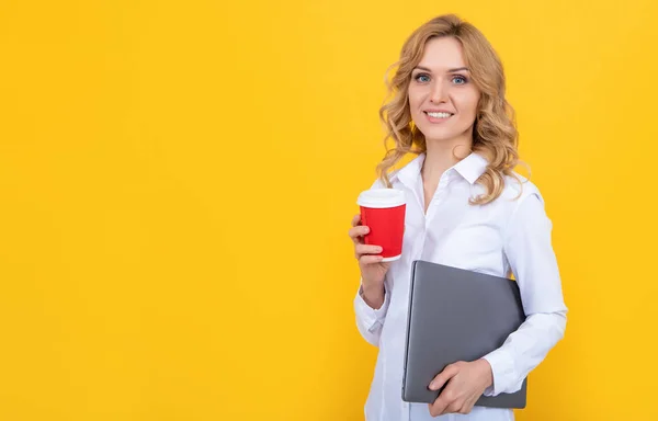 positive blonde woman with coffee cup and laptop on yellow background.