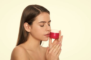 Genç kadın cilt için krem kavanozu tutuyor. Beyaz arka planda, fotokopi alanı ile izole edilmiş..