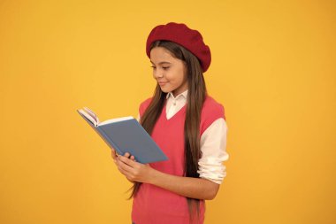 Fransız bereli mutlu genç kız sarı arka plan üzerine kitap okuyor..