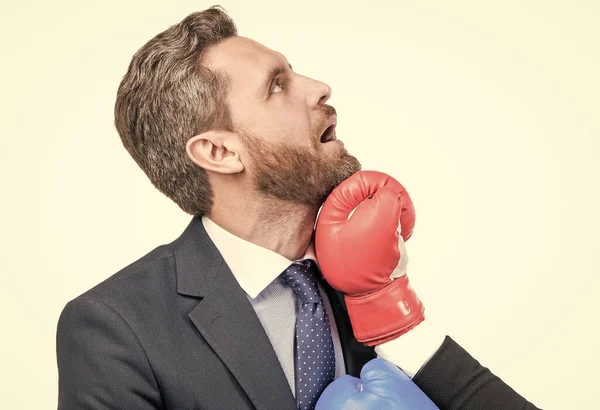 An uppercut crashes into his jaw. Businessman got punch in face. Man punched with boxing glove. Knockout punch. Workplace conflict. Business competition. Stay in the fight.