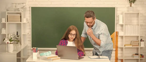 curious pupil and tutor with laptop. father and teen girl study. private teacher and child at computer. family help. dad and daughter near clackboard. back to school. childhood education.