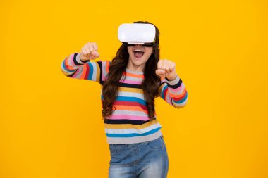 Şaşırmış bir genç. Çocuklar için sanal aletler, boş zaman ve eğitim. Genç kız sarı arka planda izole edilmiş VR gözlükleri kullanıyor. Heyecanlı genç kız