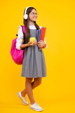 Okula dönelim. Çantalı liseli kız. Elma ve kitap tutuyor. Öğrenmeye hazır. İzole edilmiş sarı stüdyo geçmişi olan bir okul çocuğu. Mutlu yüz, pozitif ve gülümseyen genç kız duyguları