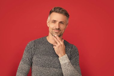 Gülümseyen yakışıklı adam kırmızı arka planda süveter giy, portre.