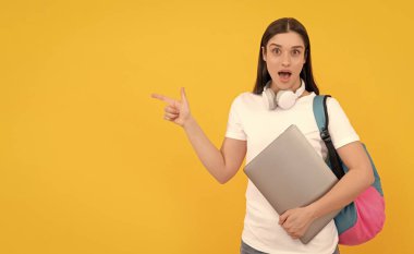 İnternetten alın. Okula dönüyorum. Etkileyici bloglar. Sırt çantalı sürpriz kız fotokopi alanını işaret ediyor. Modern eğitim için webinar. İletişim teknolojisi. Kadın kulaklıkları dizüstü bilgisayarı tutar.